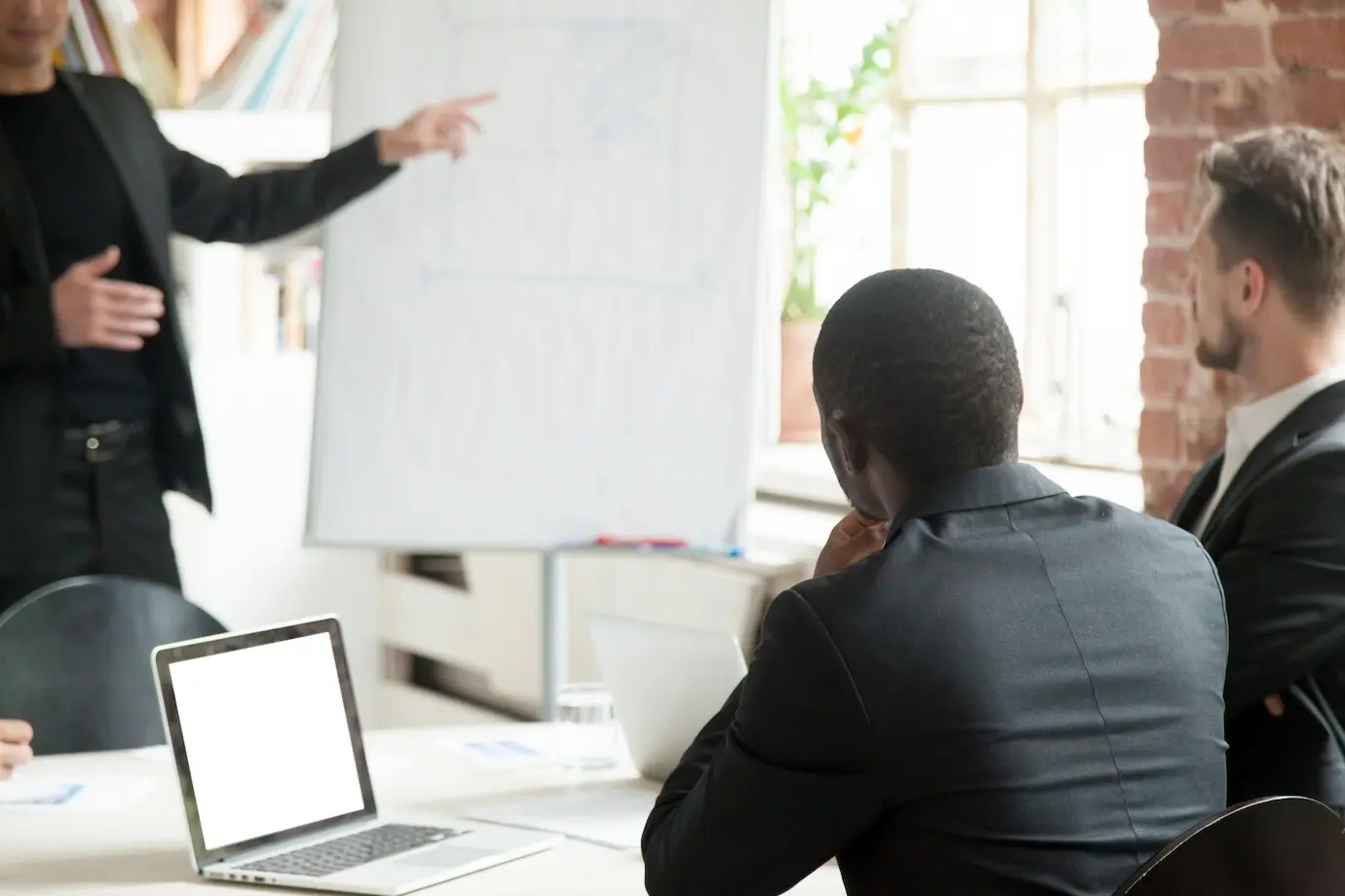 Ein Team von Geschäftsmännern hört während eines Briefings einem geschäftlichen Vortrag zu.